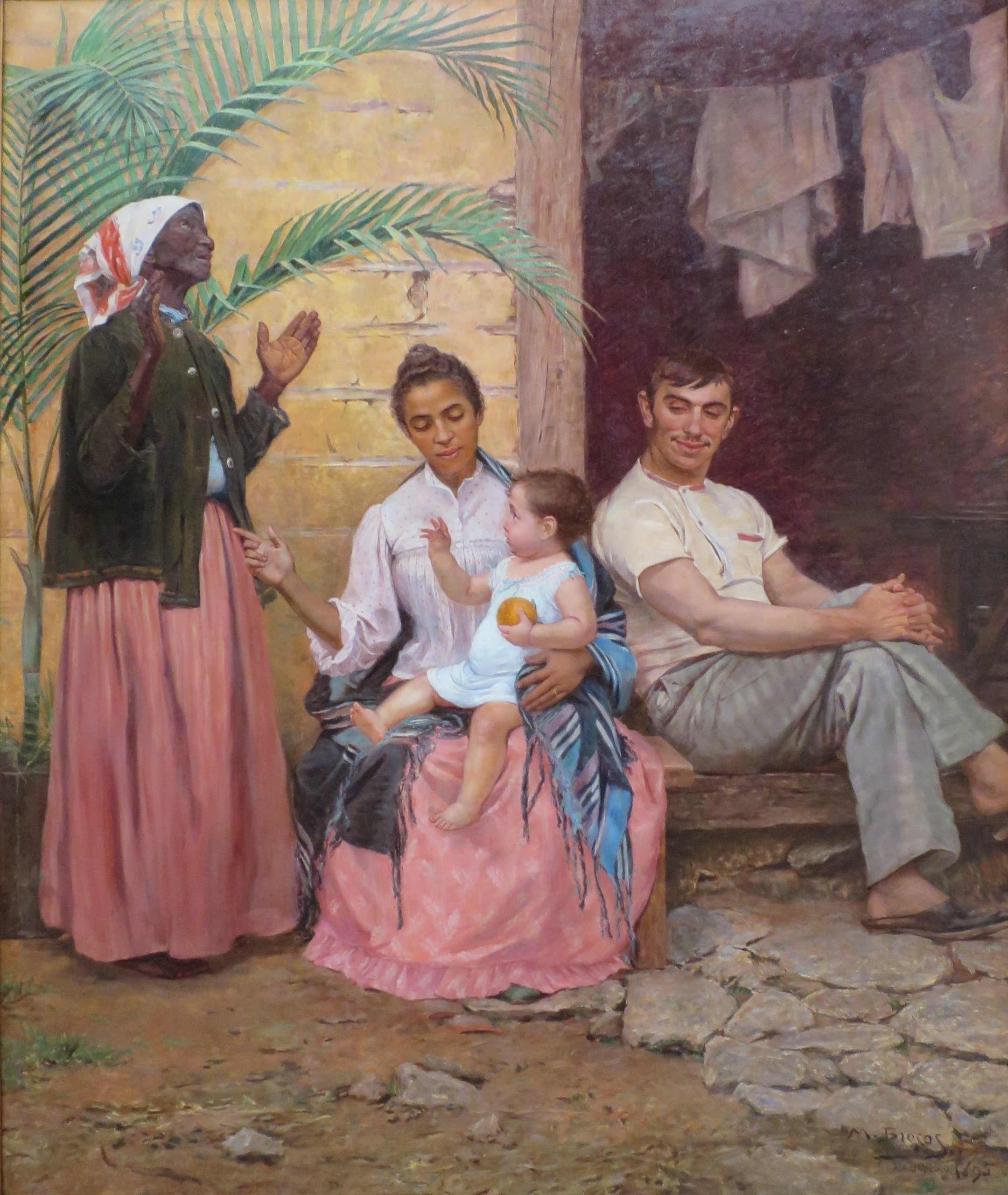 A Redenção de Cam. Modesto Brocos y Gómez, Public domain, via Wikimedia Commons. An oil painting with the image of a black grandmother standing next to a lighter-skinned, sitting mother who is holding her child on her lap. The grandmother is looking up at the sky with her hands raised.  Next to the mother, you see a seated white man, presumably the father, sitting with his legs crossed.